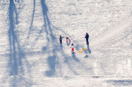 Father plays with children on a snowy playground.の写真素材