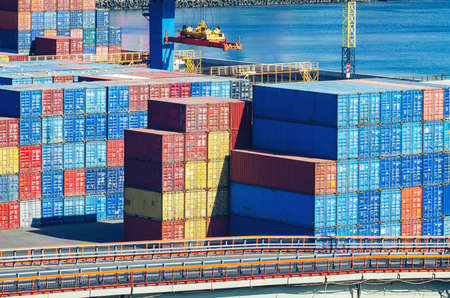 Stacked cargo containers in storage area of freight sea port.