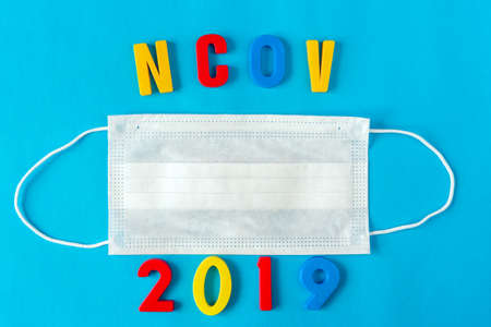 Medical respiratory disposable mask for protection against viruses on a blue background, with the words ncov 2019.の写真素材