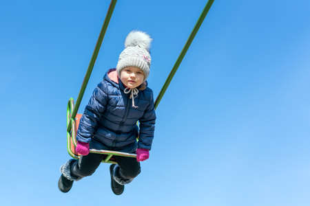 Little happy girl swinging on a swing.の写真素材