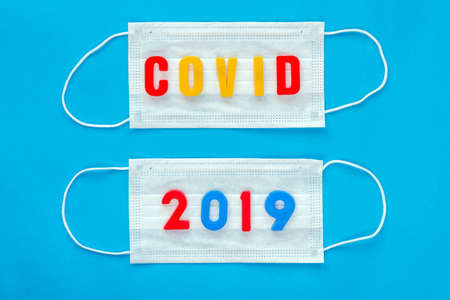 Medical respiratory disposable mask for protection against viruses on a blue background, with the words covid 2019.の写真素材