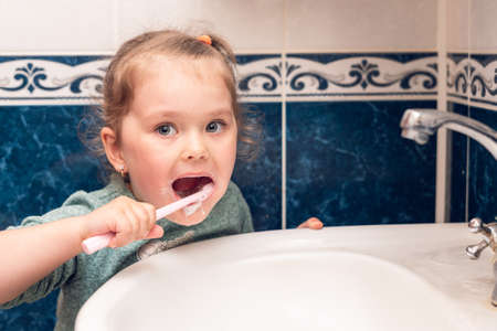 Little girl brushes her teeth in the morning in the bathroom.の写真素材
