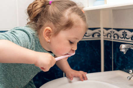 Little girl brushes her teeth in the morning in the bathroom.の写真素材