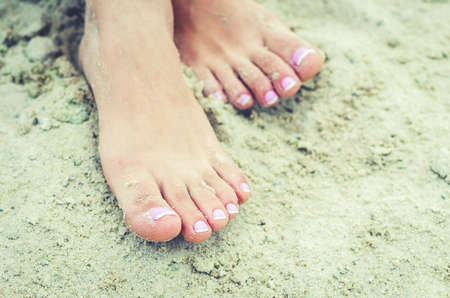 Female legs in the sand with a french pedicure.の写真素材