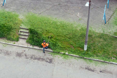 Man trimmer cuts grass in the city, top view.の写真素材