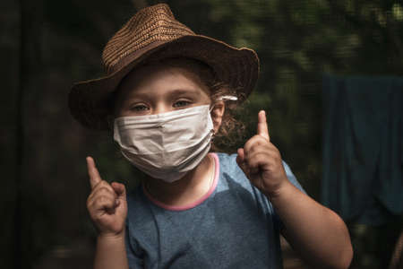 Portrait of a little girl in a medical mask on the street. Pandemic coronavirus Covid-19, virus protection.の写真素材