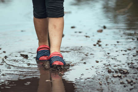 Children's feet walking in a muddy puddle after the rain.の写真素材