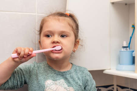 Little girl brushes her teeth in the morning in the bathroom.の写真素材