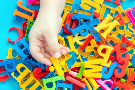Child holding magnetic plastic letters in hands.