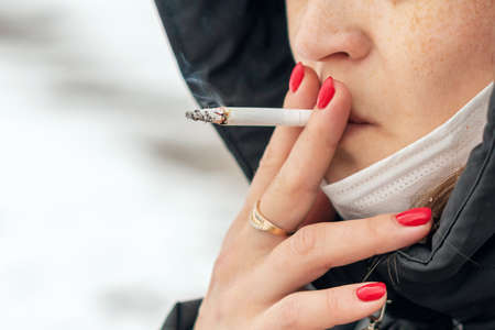 Young girl smokes a cigarette, close up.の写真素材