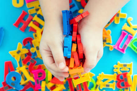Child holding magnetic plastic letters in hands.