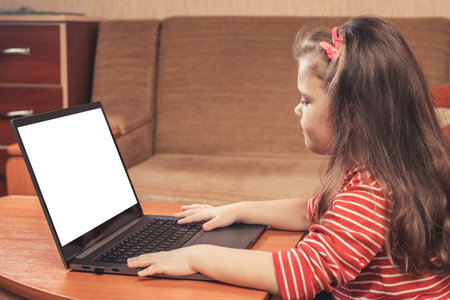 Little girl using laptop for distance learning or for fun.