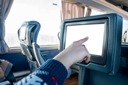 The interior of the bus with an interactive touch screen, a woman's hand touches the screen installed on the seat in a long-distance bus.の写真素材