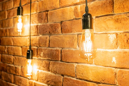 Decorative incandescent bulbs in Edison style on a brick wall background.の写真素材