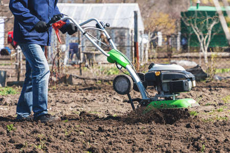 Farmer man plows the land with a cultivator preparing the soil for sowing.の写真素材