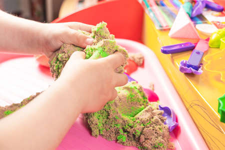 Hands of a child playing with multicolored kinetic sand.の写真素材