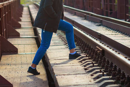 A woman steps over the rails in an unidentified place for passage.の写真素材