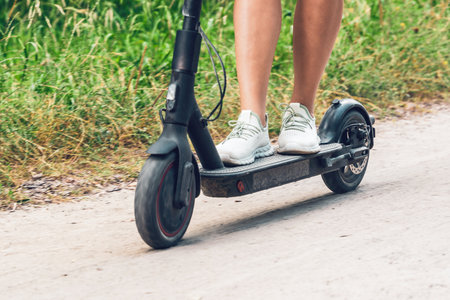 Female feet on an electric scooter riding on a dirt road.の写真素材