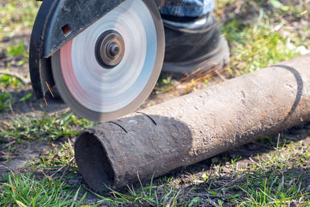 Worker cuts metal with an angle grinder.