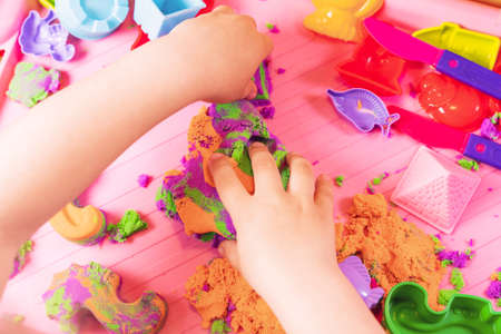 Hands of a child playing with multicolored kinetic sand.の写真素材