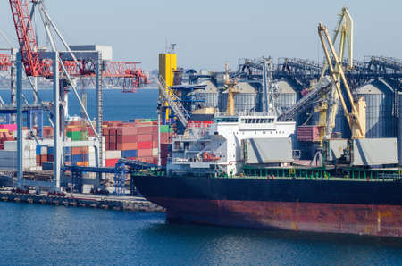 Port cargo crane loads a container onto a cargo ship in a seaport.の写真素材