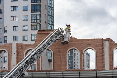 Kharkiv Ukraine, February 21, 2020: A worker in a construction cradle dismantles the facade of an old building.のeditorial素材