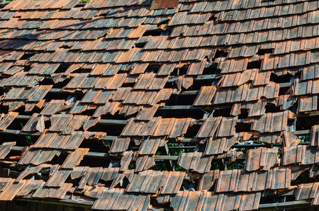 Roof of an old abandoned house with broken and fallen tiles.の写真素材