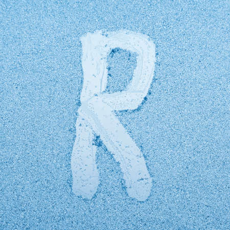 The letter R written on glass with frost in the frost in winter, close up.の写真素材
