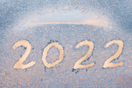 Inscription 2022 on a frozen window with patterns.の写真素材