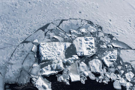 Broken ice surface of lake in winter, background texture.