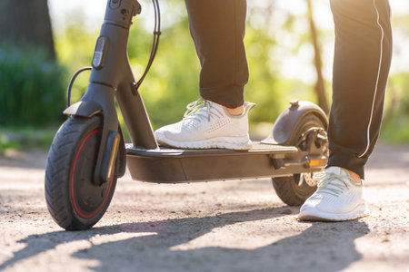 Young woman on an electric scooter on a dirt road in the park.の写真素材