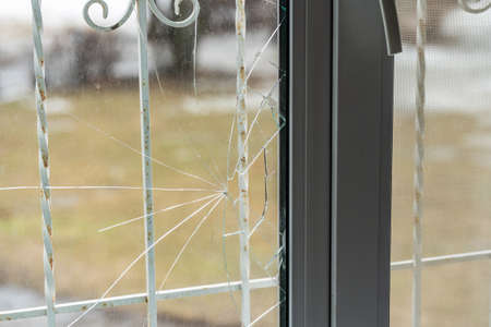 Glass broken by hooligans in a metal-plastic window, close-up.