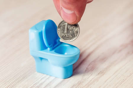 The hand lowers the Russian ruble into a toy toilet bowl, devaluation, depreciation of the ruble.の写真素材
