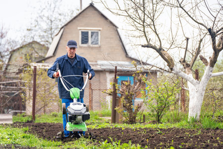 Farmer man plows the land with a cultivator preparing the soil for sowing.の写真素材