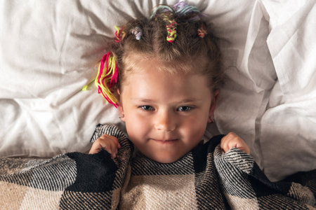 Portrait of cute adorable smiling little girl waking up in her bed.