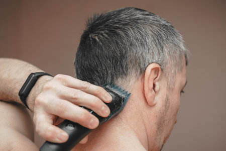 Man cutting his own hair with a clipper.の写真素材