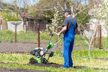 Farmer man plows the land with a cultivator preparing the soil for sowing.の写真素材