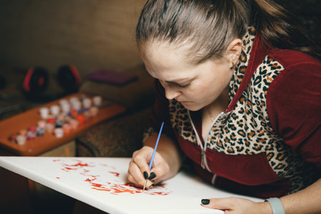 Girl paints a picture by numbers with paints.の写真素材