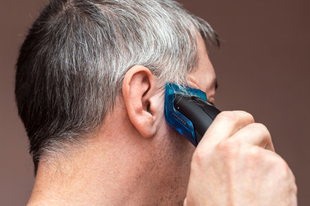 Man cutting his own hair with a clipper.の写真素材