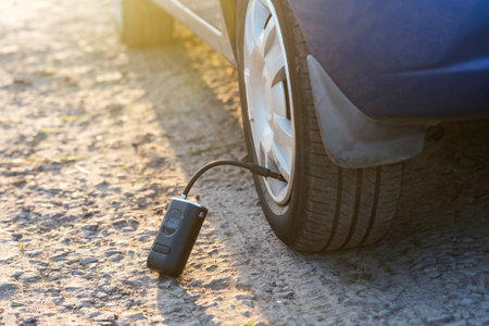 Inflating car tires with a portable wireless air pump outdoor.