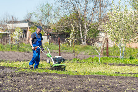 Farmer man plows the land with a cultivator preparing the soil for sowing.