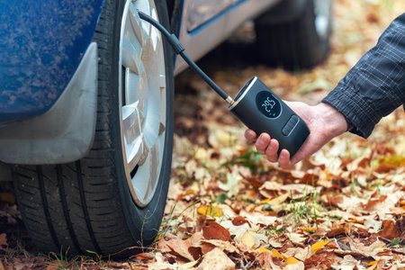 Inflating car tires with a portable wireless air pump outdoor.