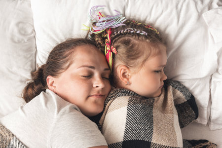 Young mother with daughter sleeping in bed.の写真素材