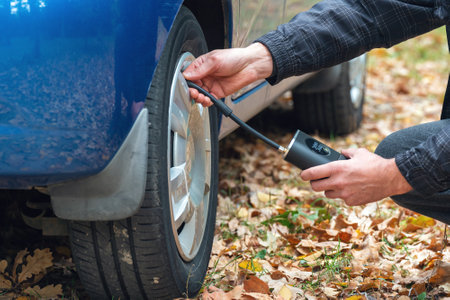 Inflating car tires with a portable wireless air pump outdoor.の写真素材