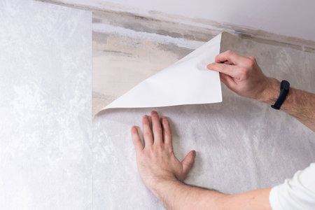 A man is gluing non-woven wallpaper on the wall. Room renovationの写真素材