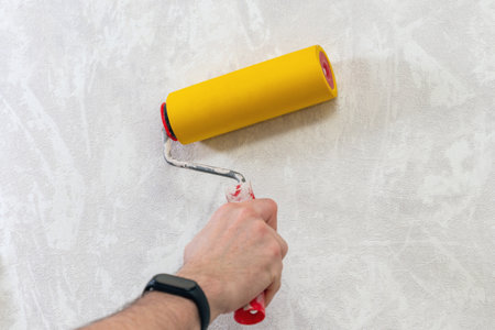A man's hand with a roller for smoothing wallpaper. Wallpapering the apartment.の写真素材