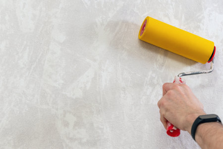 A man's hand with a roller for smoothing wallpaper. Wallpapering the apartment.