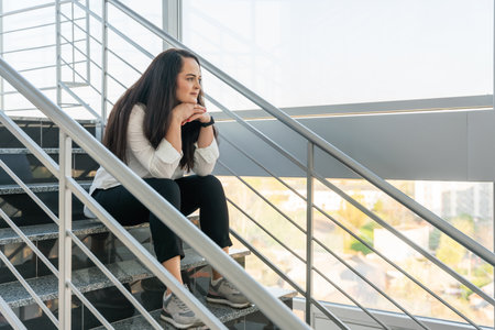 Portrait of a beautiful girl sitting on the stairs and thinking about something.の写真素材