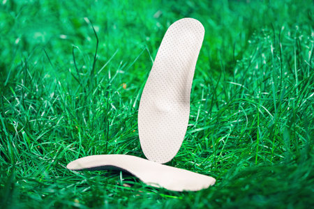 Orthopedic insoles for shoes on a background of green grass.