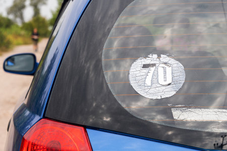 Old worn out sticker 70 on the rear window of a car.の写真素材
